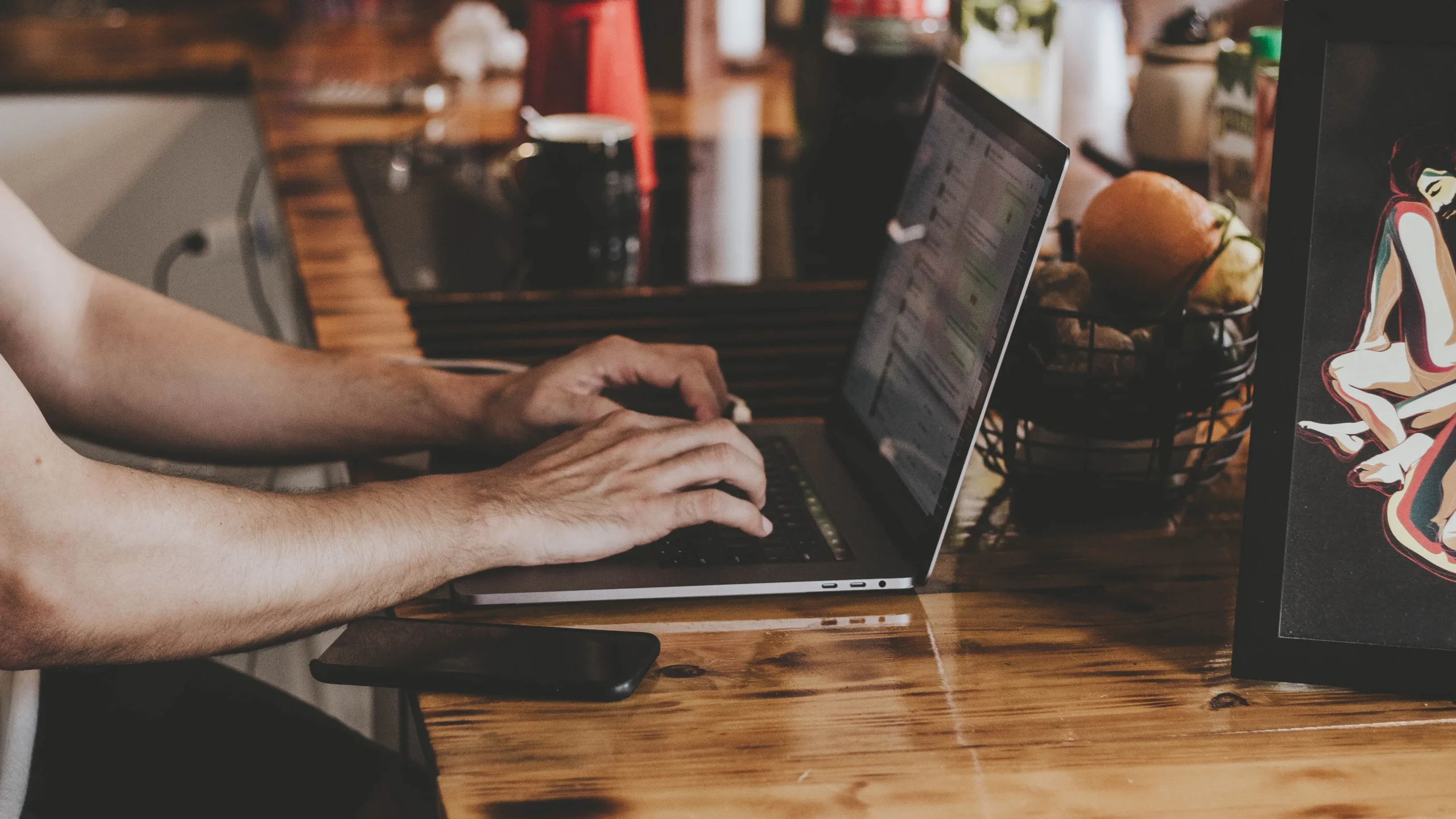 person-in-front-of-laptop-on-brown-wooden-table-2115217